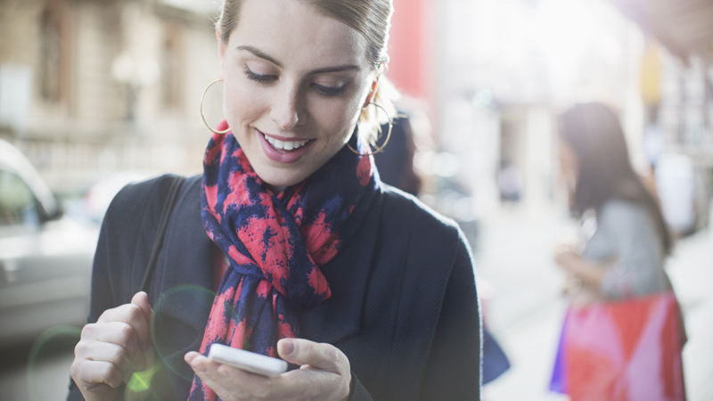 Woman using mobile phone on city street.