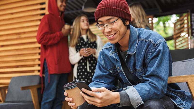 Hombre Gen z sonriente usando el teléfono